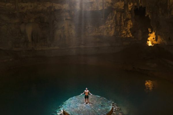 Explore a breathtaking cenote with sunrays filtering through limestone formations in Cancún.